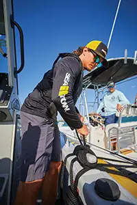 sea tow captain tying line to cleat to secure boat to member's boat